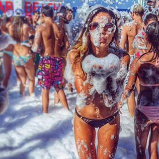An adult woman blowing bubbles at a foam party
