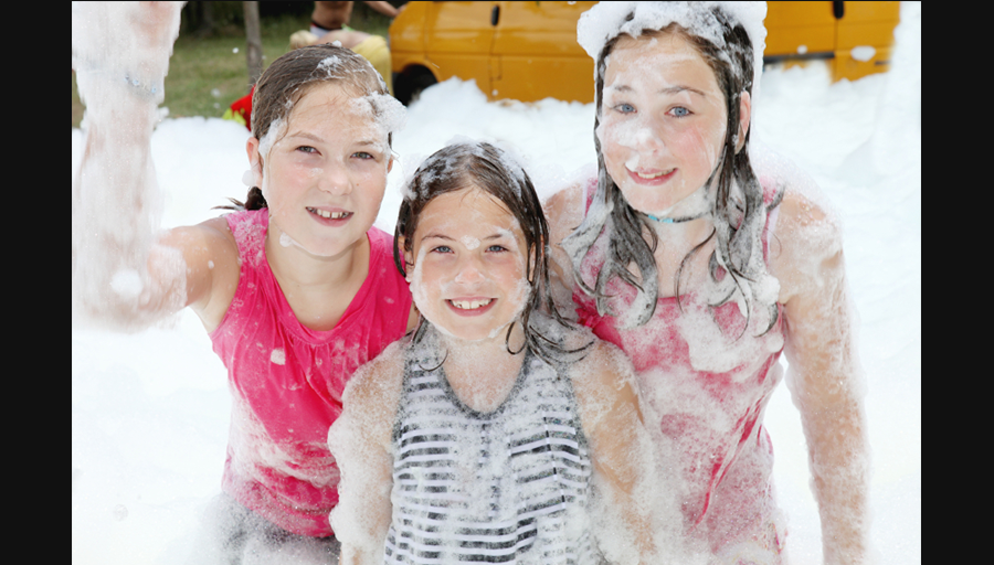 Three girls posing for the camera, covered in foam