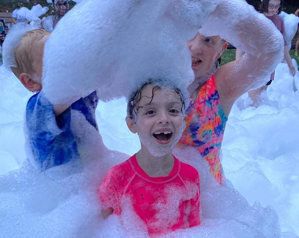 A young girl with foam on her head laughing - foam parties CT, MA, RI